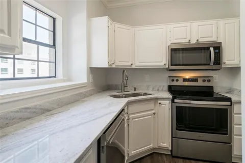 a kitchen with cabinets stainless steel appliances and a window