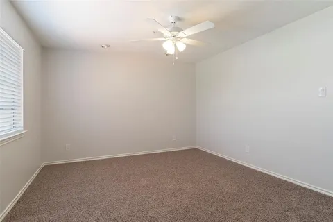 an empty room with a window and a fan