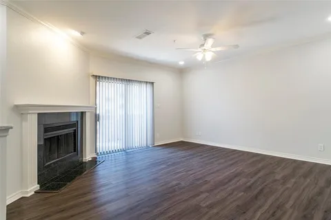 an empty room with wooden floor fireplace and windows