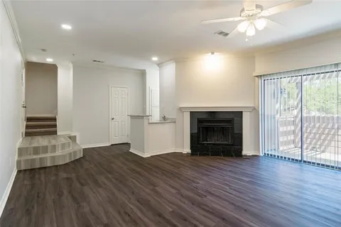 an empty room with wooden floor fireplace and windows