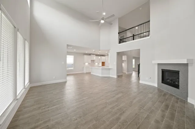an empty room with wooden floor fireplace and windows