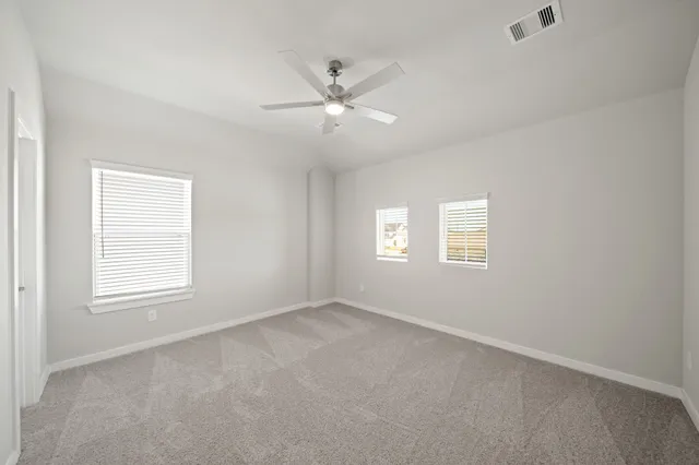 an empty room with windows and fan