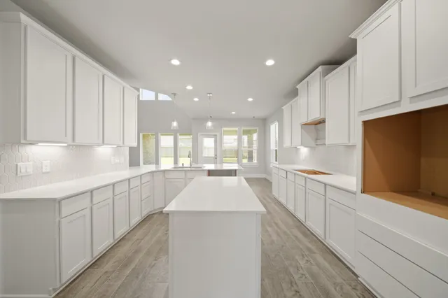 a large white kitchen with kitchen island a sink a center island stainless steel appliances and a counter space
