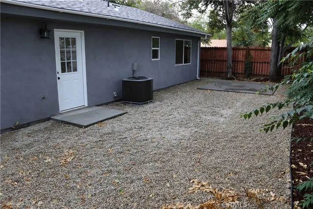 a backyard of a house with wooden fence and a tree