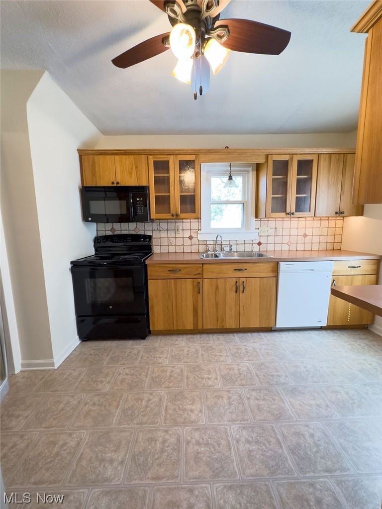 Kitchen featuring black appliances, brown cabinets, ceiling fan, backsplash, and light tile floors