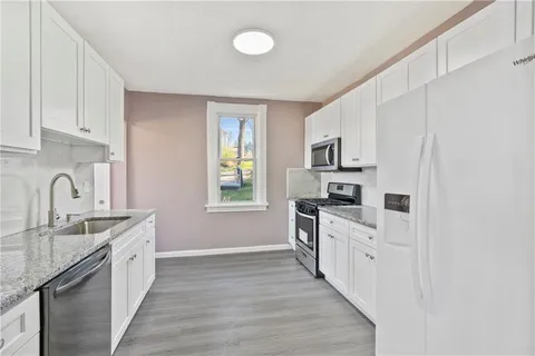 a kitchen with granite countertop a sink stove a refrigerator and a stove