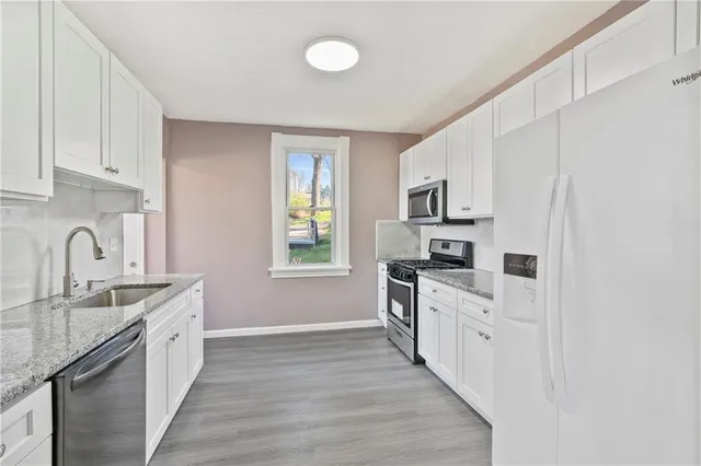 a kitchen with granite countertop a sink stove a refrigerator and a stove