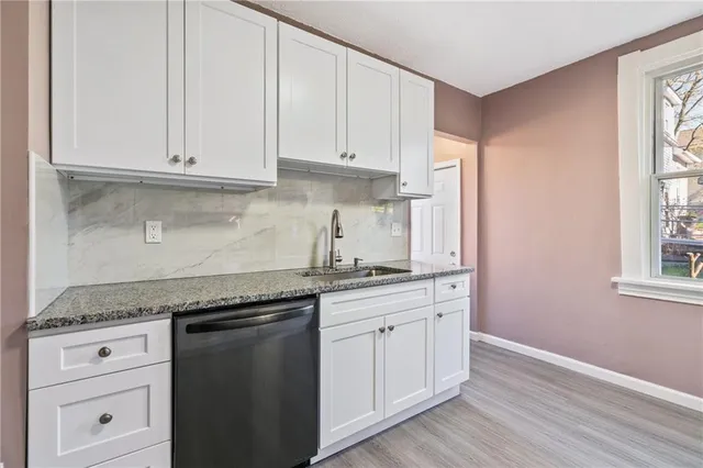a kitchen with granite countertop white cabinets and a sink