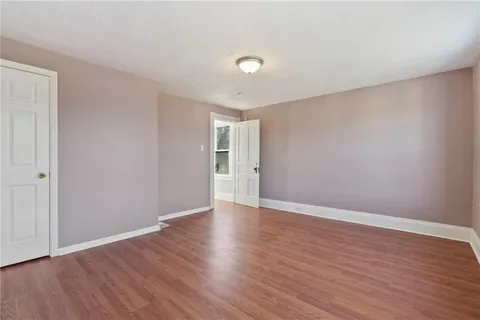a view of an empty room with wooden floor and closet