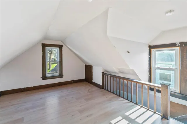 a view of an empty room with wooden floor and window