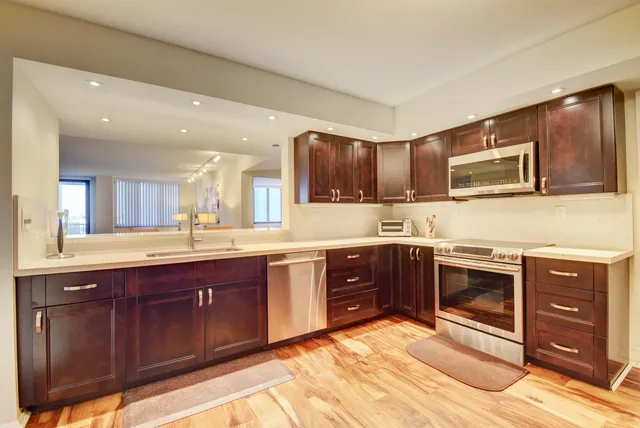 a kitchen with stainless steel appliances granite countertop wooden cabinets and a stove top oven