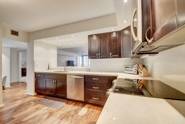 a kitchen with stainless steel appliances granite countertop a sink a stove and a wooden floors