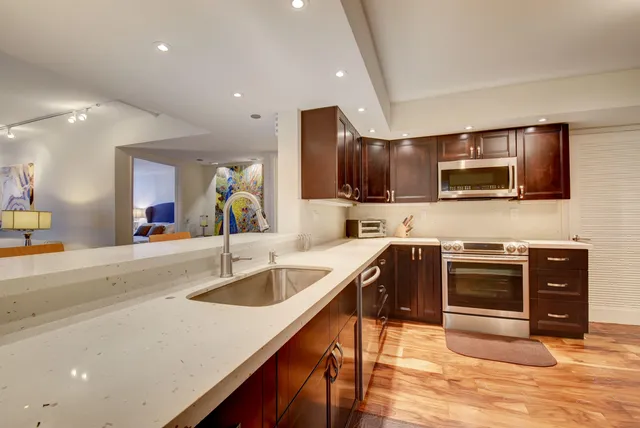 a kitchen with stainless steel appliances granite countertop a sink and a stove top oven with wooden floor