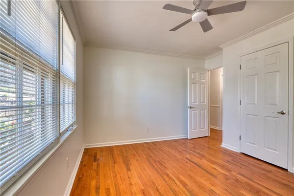 a view of empty room with wooden floor and fan
