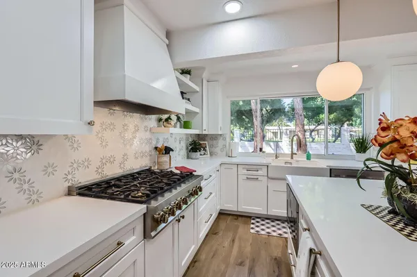 a kitchen with a stove a sink a window and cabinets