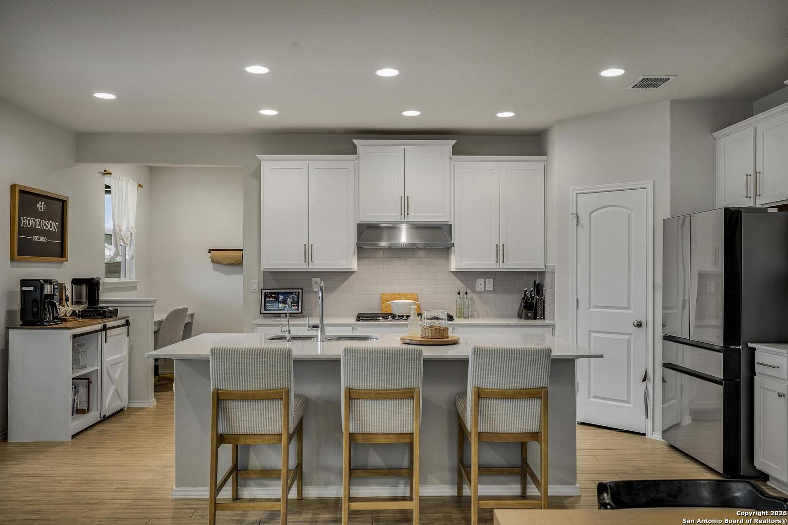151 Inverness Boerne, TX 78015 - Photo 7 of 31 a kitchen with kitchen island granite countertop a table chairs refrigerator and microwave
