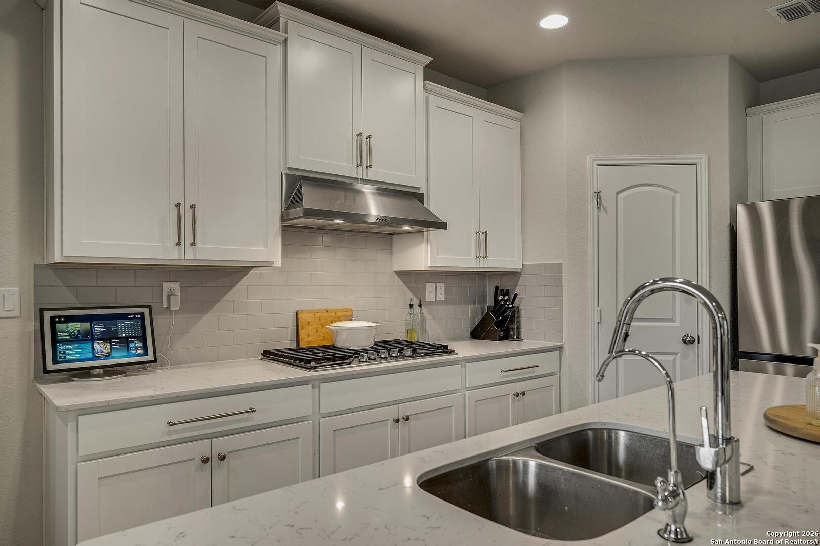 151 Inverness Boerne, TX 78015 - Photo 10 of 31 a kitchen with white cabinets a sink and a stove with wooden floor