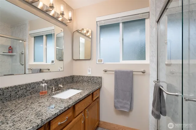 a bathroom with a granite countertop sink a mirror and a shower