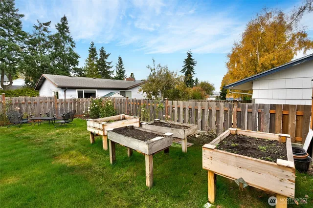 a backyard of a house with table and chairs plants and large tree