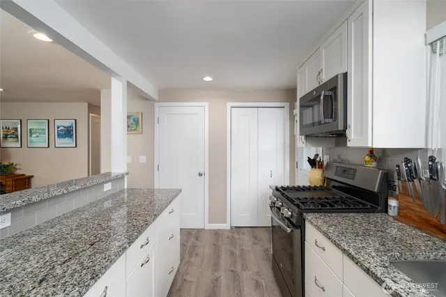 a kitchen with granite countertop stainless steel appliances window a stove and a sink