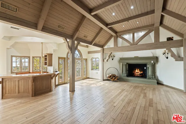 a view of an empty room with wooden floor fireplace and a window