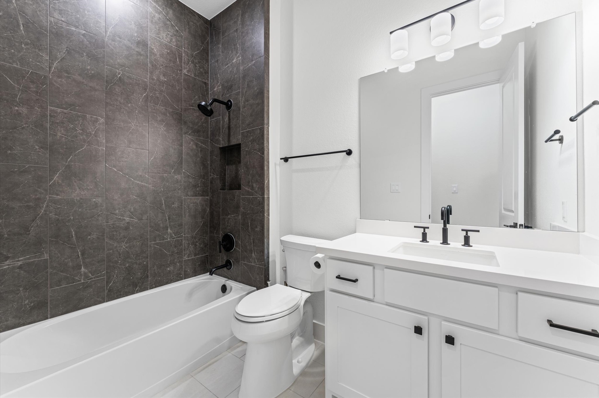 7327 Trial Rdg Drive Fulshear, TX 77441 - Photo 15 of 26 The primary bath brings the spa home — floor-to-ceiling dark tile in the walk-in shower, double vanity, and finishes that feel intentional.