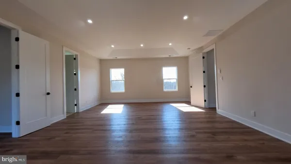 a view of an empty room with wooden floor and windows