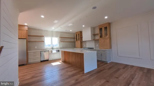 a kitchen with stainless steel appliances wooden floors and white cabinets
