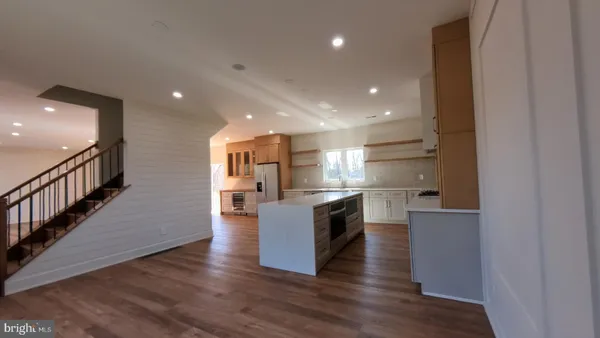 a large kitchen with stainless steel appliances granite countertop a large counter top and wooden floors