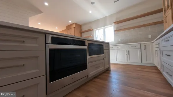a view of an empty room and wooden floor in kitchen