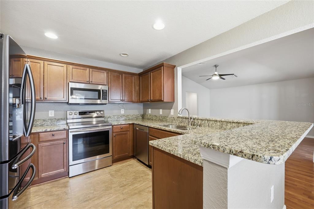 306 Stone Point Lane Lady Lake, FL 32159 - Photo 15 of 39 a kitchen with granite countertop a sink stove and refrigerator