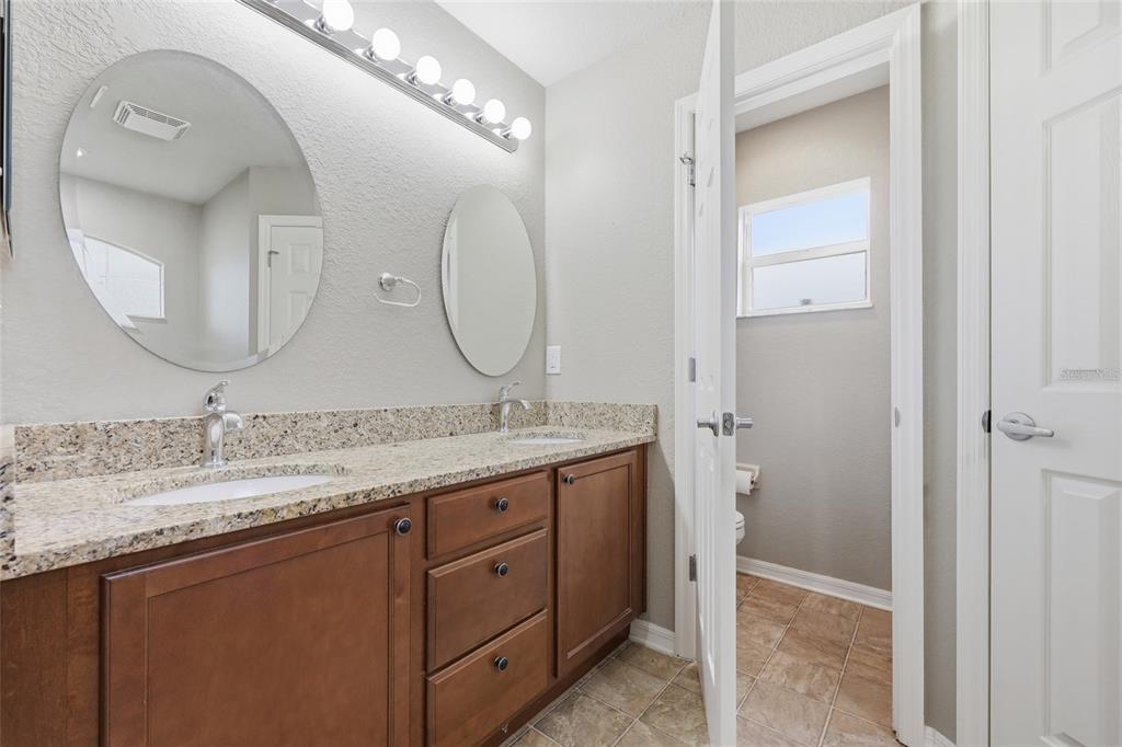 306 Stone Point Lane Lady Lake, FL 32159 - Photo 24 of 39 a bathroom with a granite countertop double vanity sink and a mirror