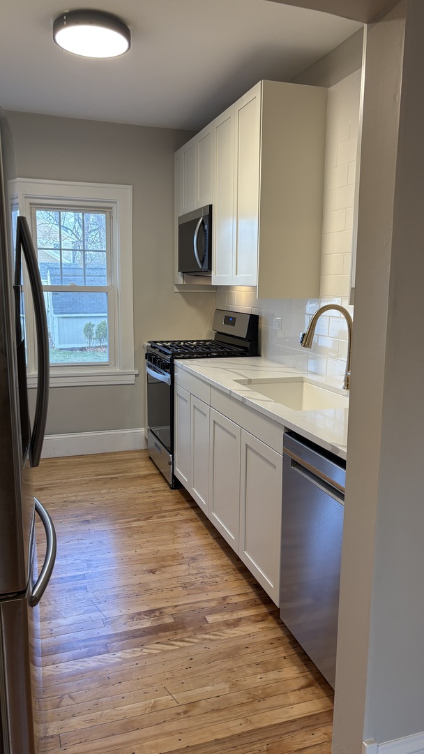 421 East Indiana Street Wheaton, IL 60187 - Photo 37 of 37 a kitchen with stainless steel appliances granite countertop a sink a stove top oven a chimney wooden floor and cabinets