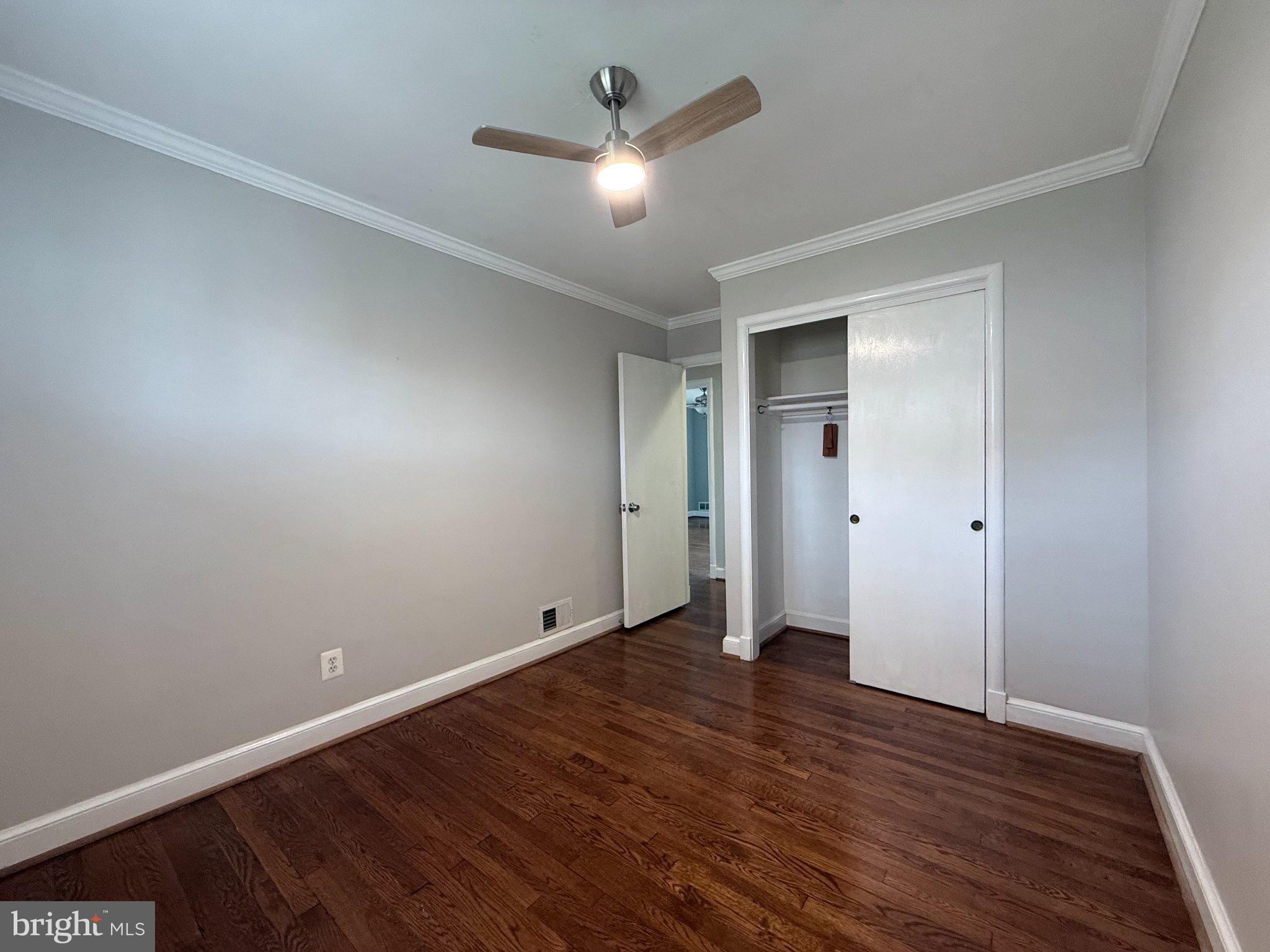 9709 Saxony Road Silver Spring, MD 20910 - Photo 29 of 47 an empty room with wooden floor and a ceiling fan
