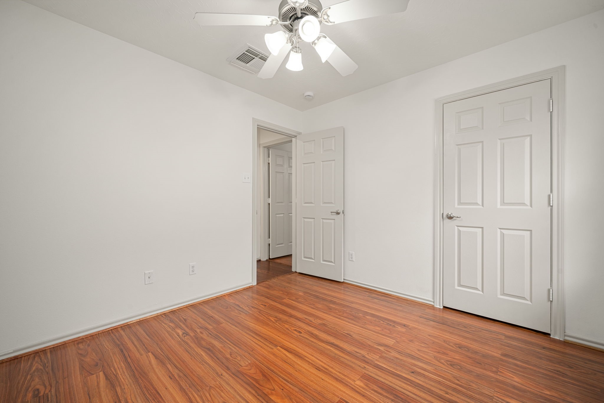 13410 Baron Hill Lane Rosharon, TX 77583 - Photo 26 of 40 an empty room with wooden floor chandelier fan and closet area with wooden floor