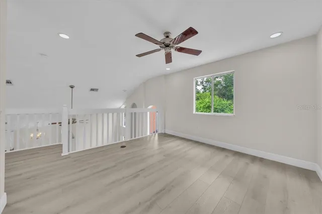 an empty room with wooden floor and a ceiling fan