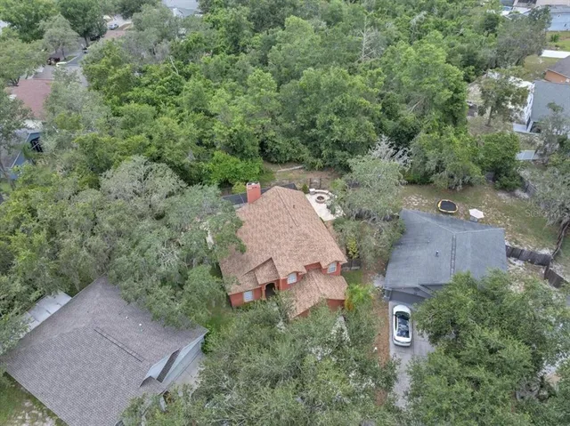 an aerial view of a house with outdoor space and trees all around