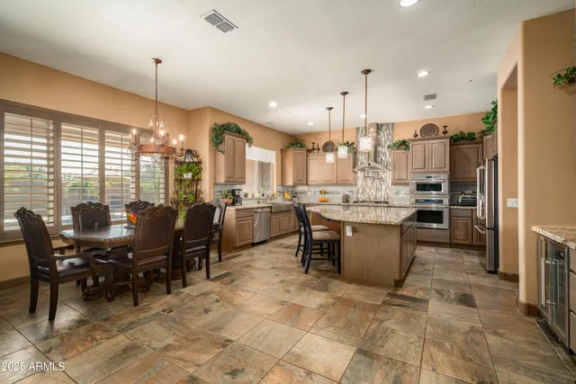 a kitchen with stainless steel appliances kitchen island granite countertop a sink table and chairs