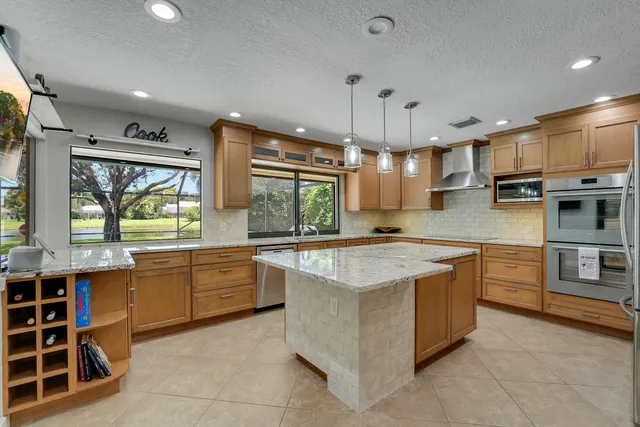 a large kitchen with kitchen island a large counter top stainless steel appliances and cabinets