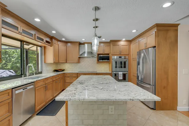 a kitchen with stainless steel appliances granite countertop a sink a stove and a wooden floors