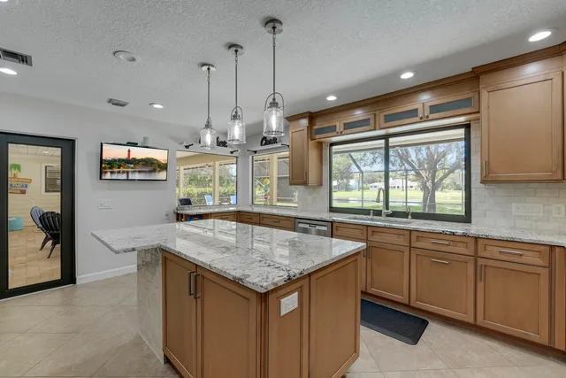 a kitchen with granite countertop a sink and white cabinets next to a window