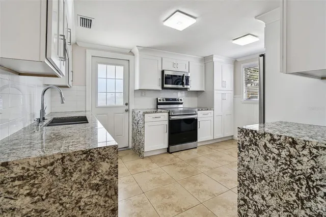 a kitchen with stainless steel appliances granite countertop a sink stove and refrigerator