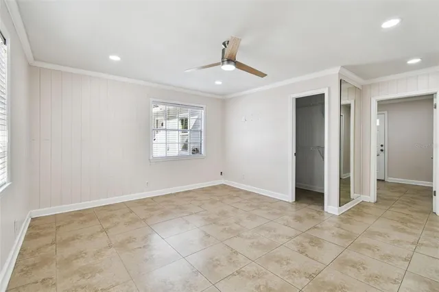 an empty room with windows and ceiling fan