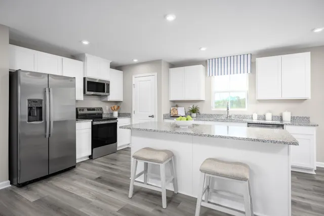 a kitchen with kitchen island granite countertop a sink cabinets stainless steel appliances and a window