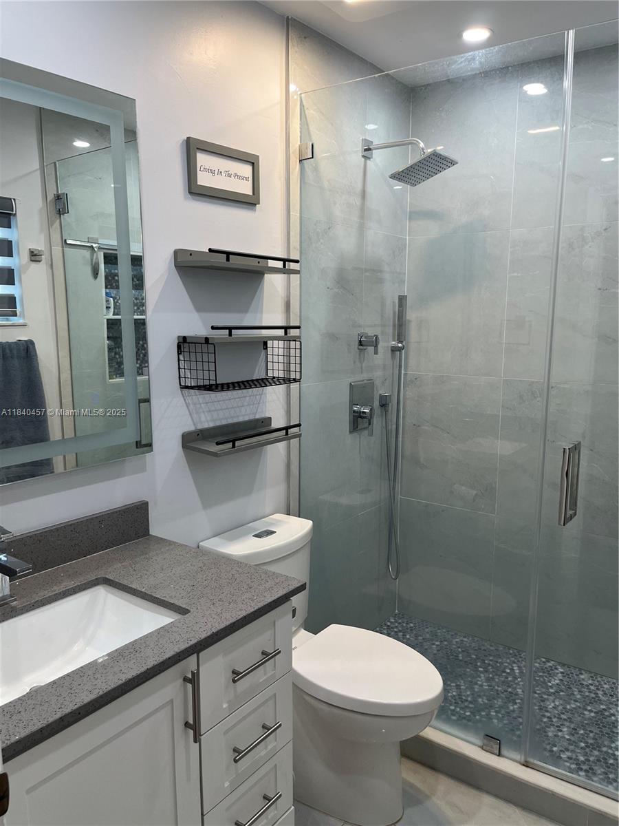9982 Southwest 162nd Court Miami, FL 33196 - Photo 67 of 97 a bathroom with a granite countertop sink a toilet a mirror and shower