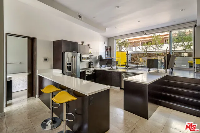 a kitchen with stainless steel appliances kitchen island granite countertop a refrigerator a stove and a dining table with wooden floor