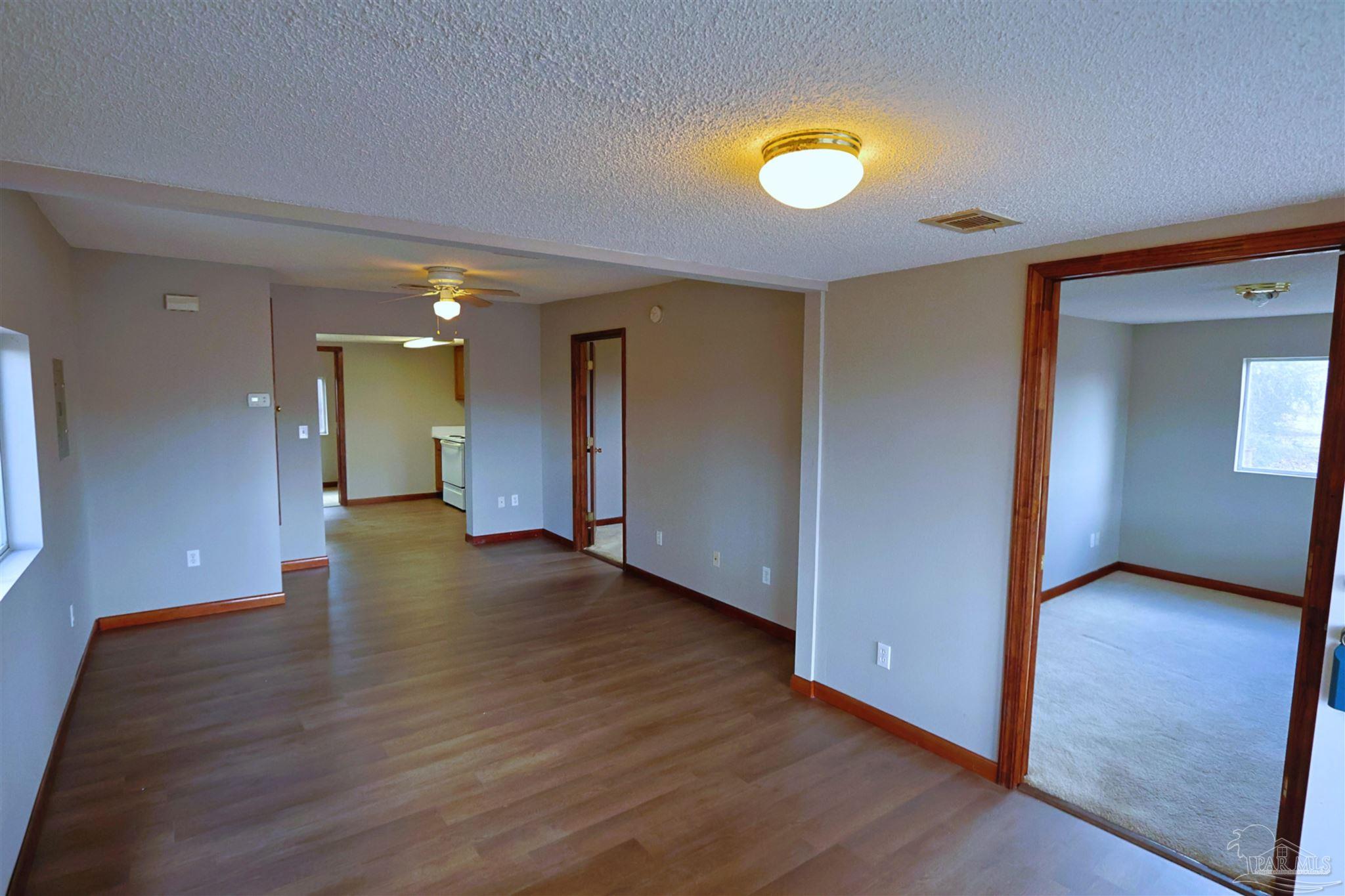 6941 Camp Henderson Road Jay, FL 32565 - Photo 4 of 17 a view of empty room with wooden floor and fan