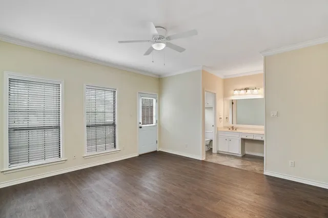 an empty room with wooden floor cabinet and windows