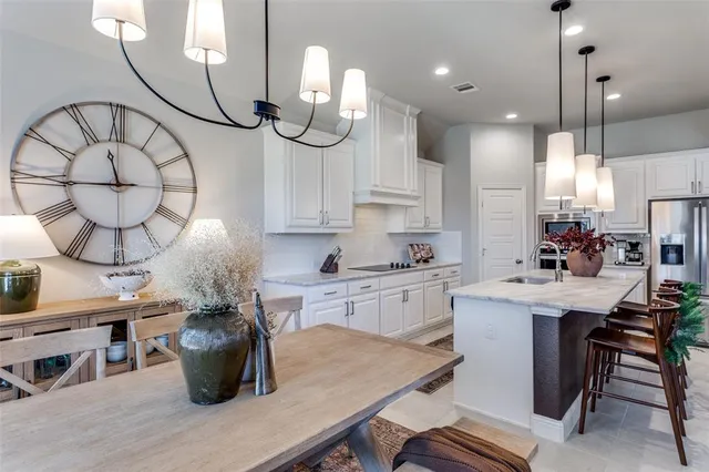 a kitchen with stainless steel appliances granite countertop a stove a sink a dining table and chairs with wooden floor