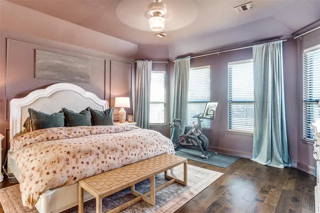 a bedroom with a bed a table and large windows